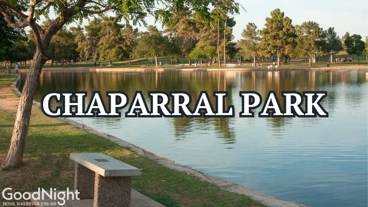 A peaceful lakeside park scene with a bench under shady trees, a tranquil lake reflecting the sky, and open walking paths. The area is serene, natural, and inviting—ideal for walking, picnicking, or simply enjoying the outdoors with a pet.